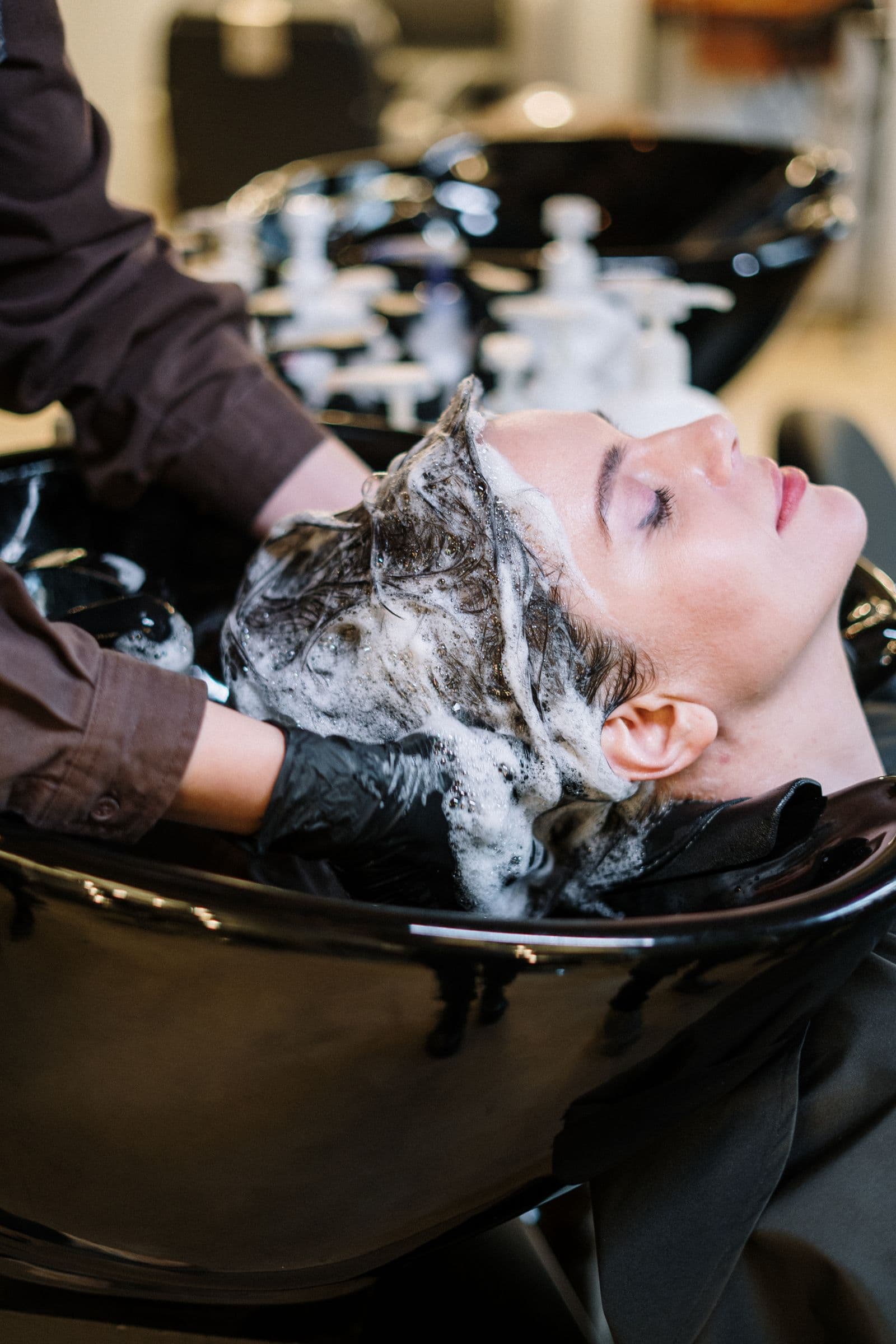 Stylist washing a client’s hair at the salon bowl